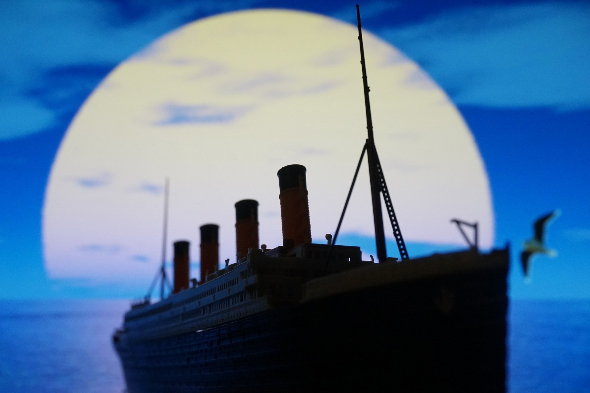 Titanic ship outlined against a large moon in blue sky