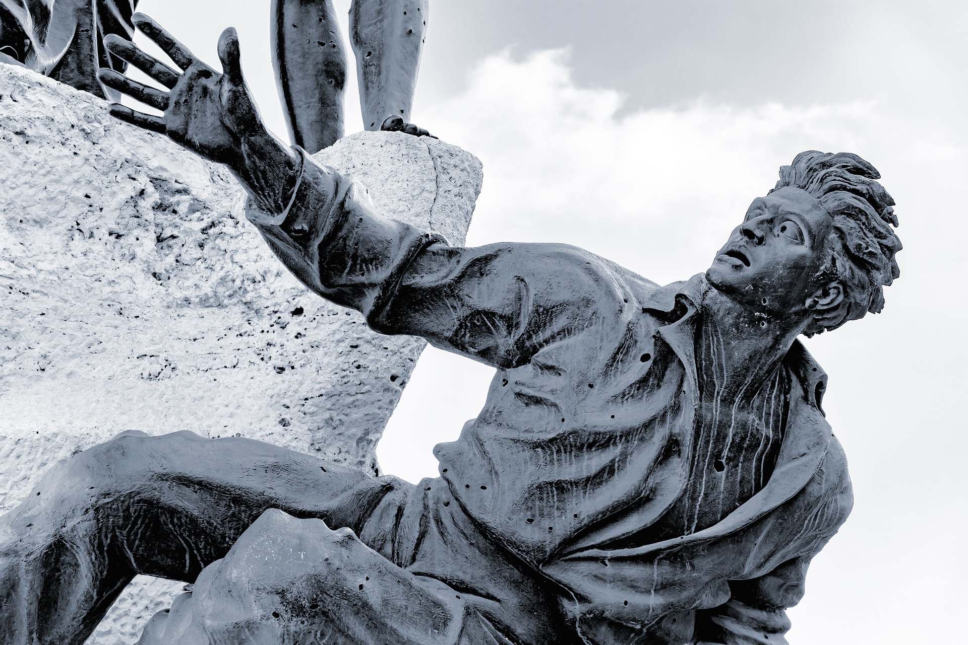 bronze statue of fallen man reaching for help