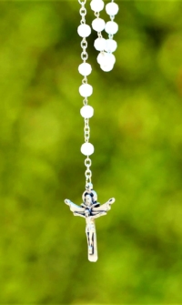 white rosary against a green background